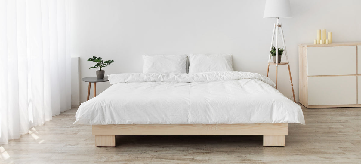 White bed with rumpled bedding in a bright minimalist bedroom