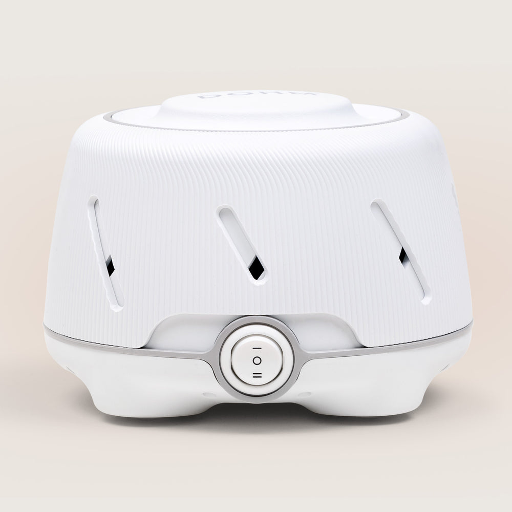 Dohm - A White sound machine with a ribbed texture and a circular switch.