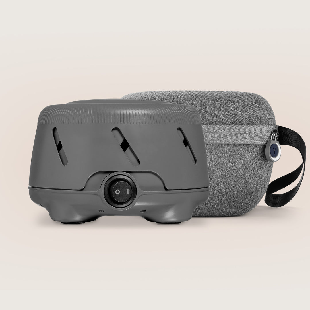 Front view of Dohm Uno white noise machine showing power dial and vents with charcoal travel case on a neutral background