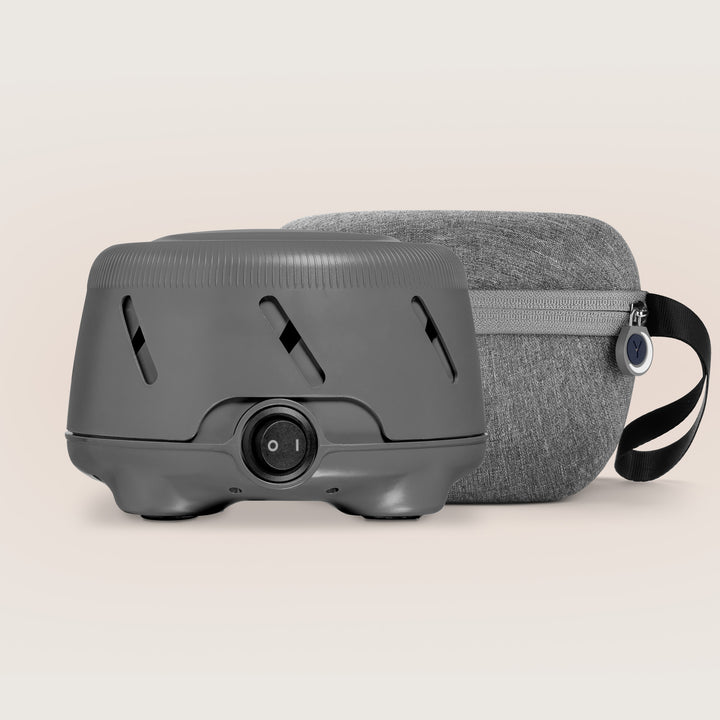 Front view of Dohm Uno white noise machine showing power dial and vents with charcoal travel case on a neutral background