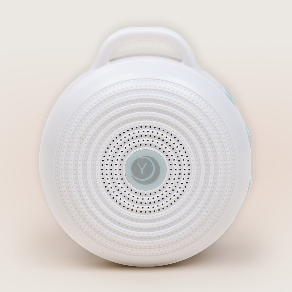 Front of Rohm white noise machine with circular speaker grille, top handle, and side control buttons on a beige background