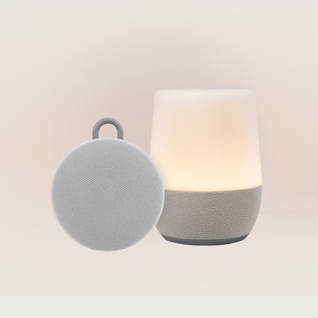 Front view of Duet sound machine and Hushh 2 speaker with warm nightlight and fabric textured base on soft neutral background