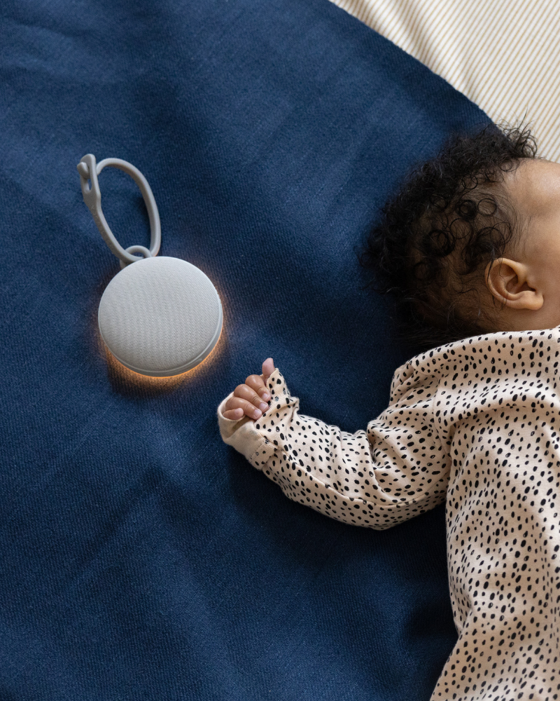 Baby resting beside a portable sound machine