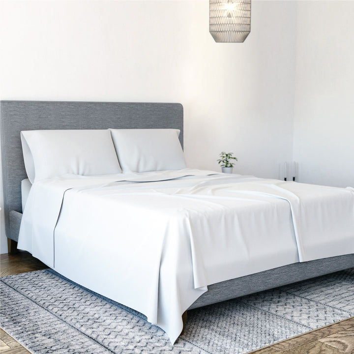 Angled view of Yogabed Essential Sleep Bundle showcasing white sheet set and pillows on a made bed in a bedroom