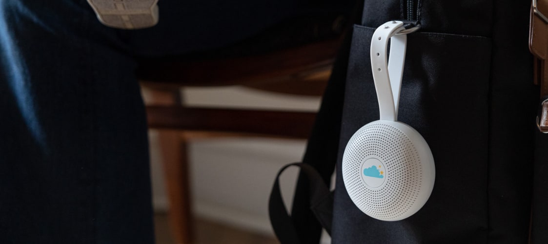 Front view of Hushh+ portable sound machine showcasing its clip attached to a backpack