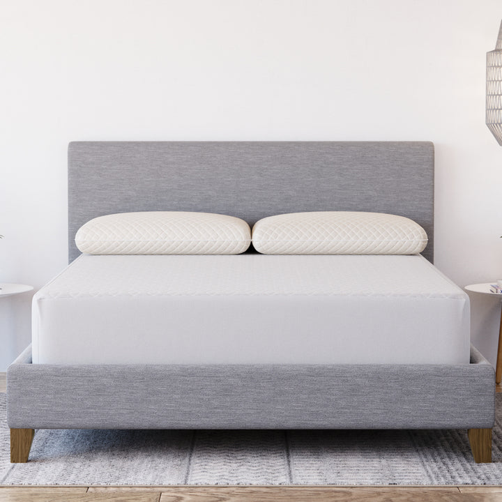 Front view of Yogabed Ultra Cool Waterproof Mattress Protector showcasing fitted coverage on a bed with gray upholstered headboard