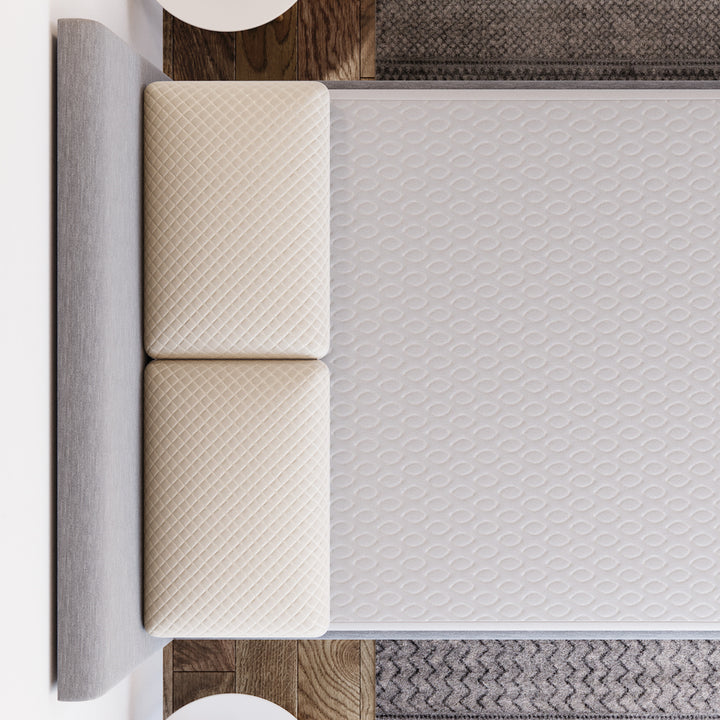 Top view of Yogabed Ultra Cool Waterproof Mattress Protector fitted over a mattress on a gray rug
