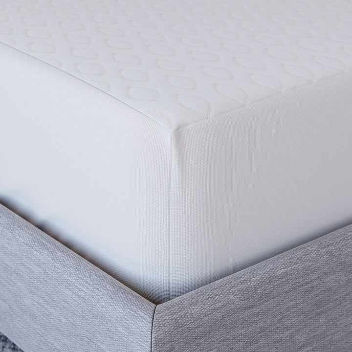 Close-up corner view of Yogabed Ultra Cool Waterproof Mattress Protector showcasing the fitted waterproof cover on a gray bed base