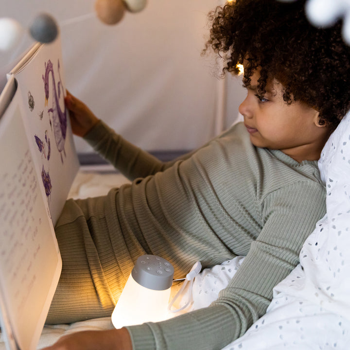 Child using a glowing Baby Soother sound machine inside a tent